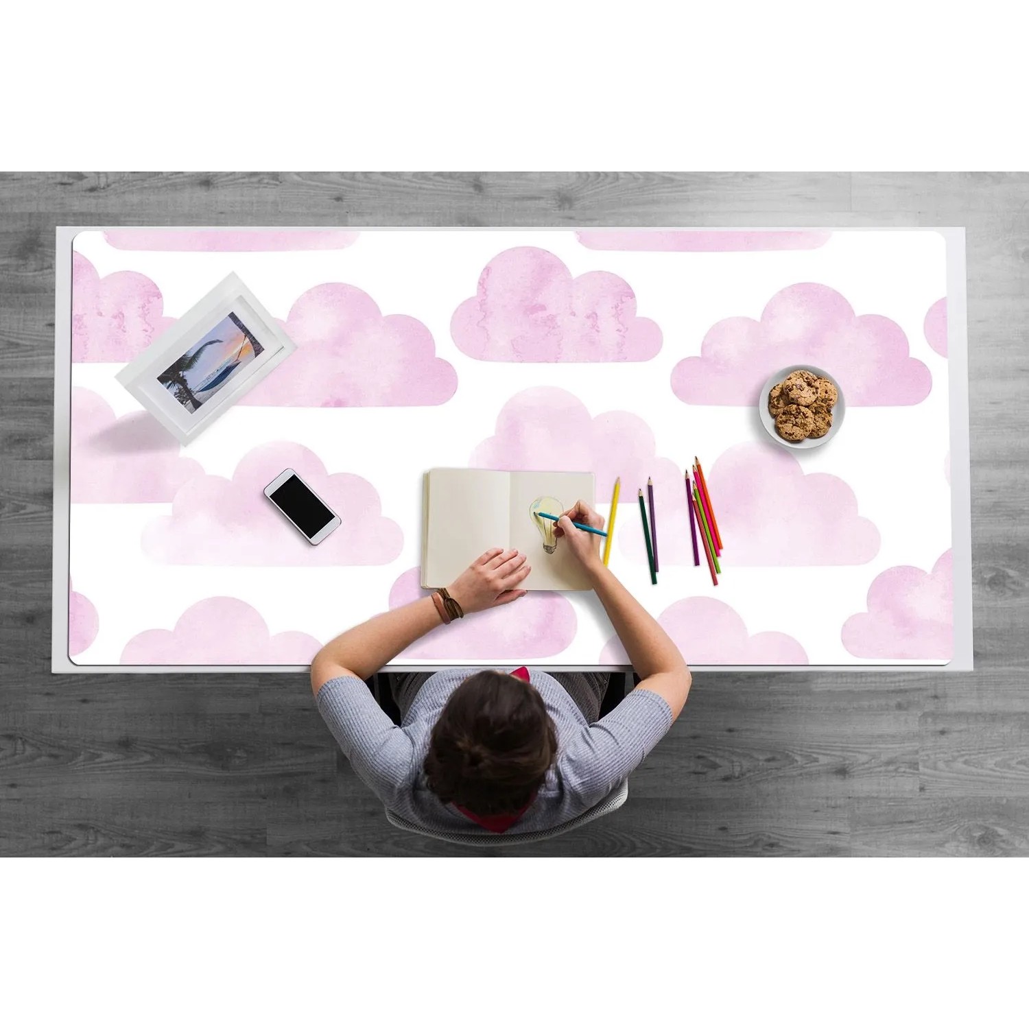 Rosa PVC Schreibtischunterlage mit Wolkenmuster, Person zeichnet am Schreibtisch. Ideal für Bürobedarf.