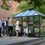 Juliana Gewächshaus Oase 13 Anthrazit mit Personen im Garten. Begehbares Glas-Gewächshaus mit Aluminiumrahmen.