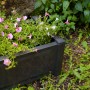 Rechteckiger, anthrazitfarbener KHW Pflanzkasten mit rosa Blüten im Garten.