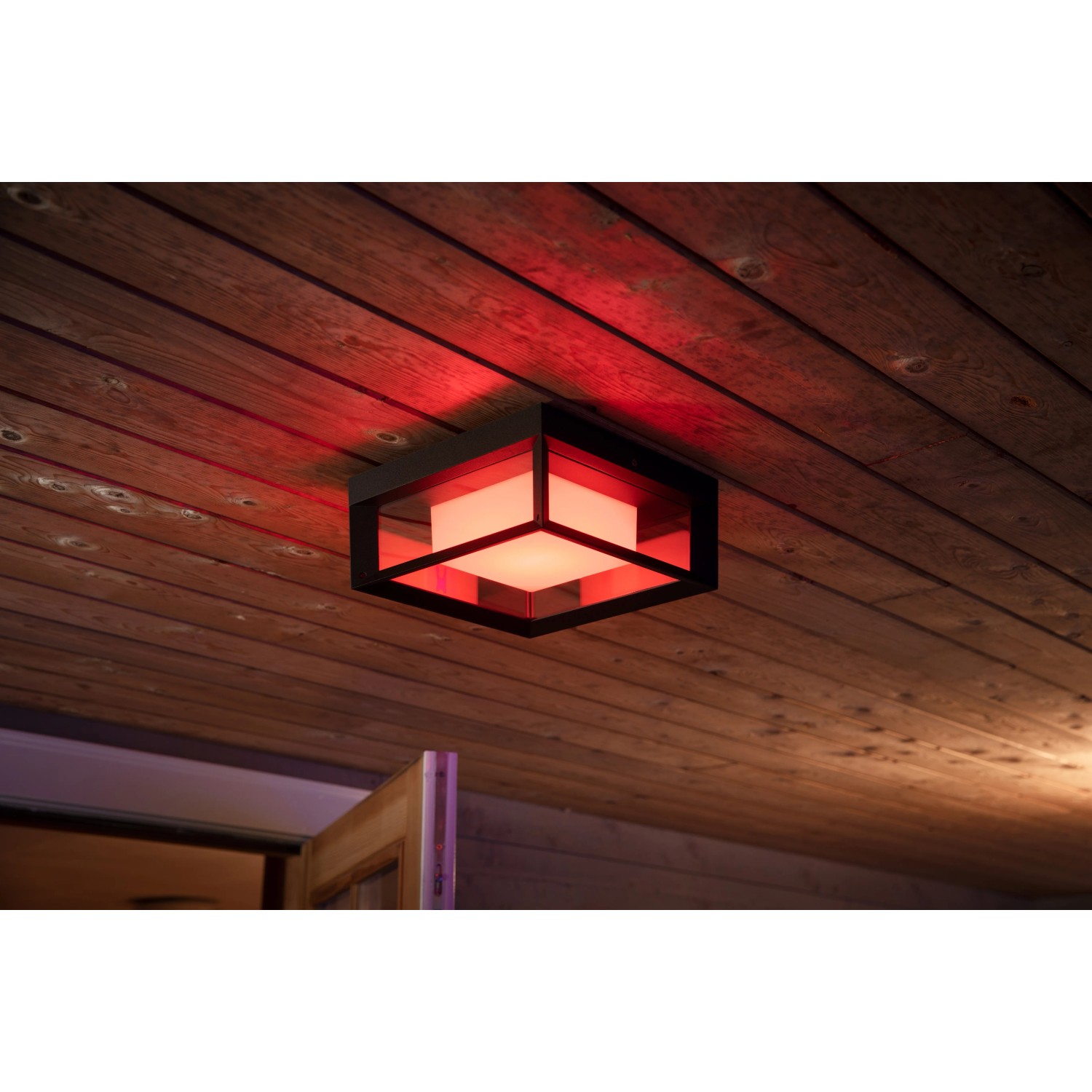 Quadratische Philips Hue Econic LED-Wandleuchte mit Farbwechsel, montiert an einer Holzdecke.