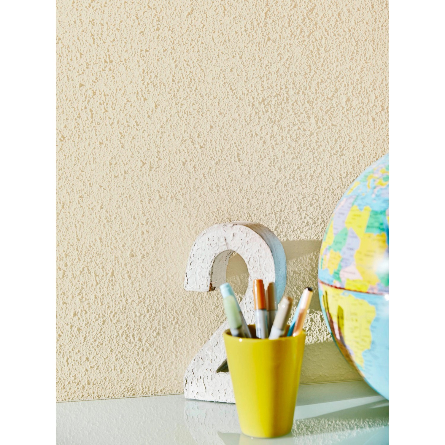 Wand mit Knauf Compact Color Honiggelb Putz, mit Deko-Elementen wie Stiften und Globus.