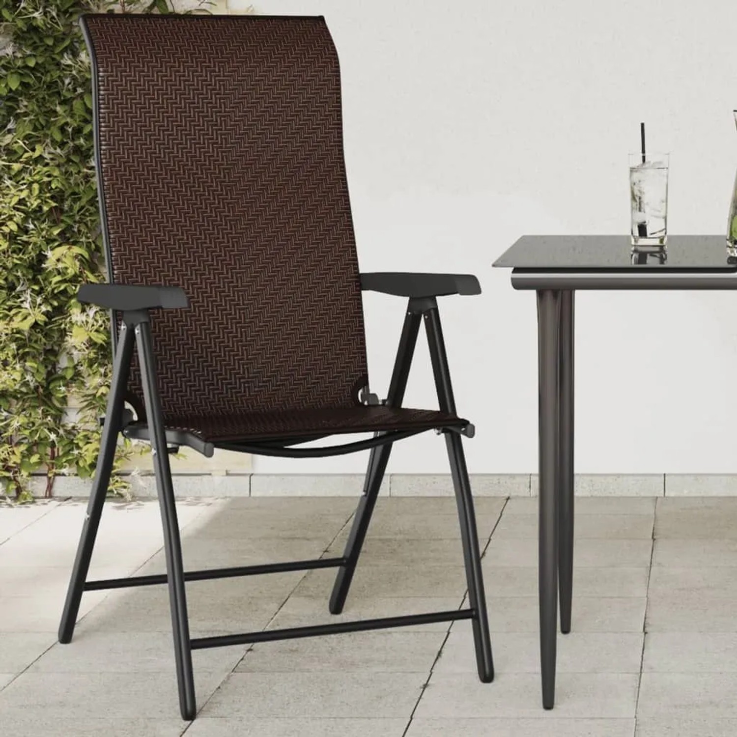 Brauner klappbarer Gartenstuhl aus Poly Rattan mit schwarzem Stahlgestell auf Terrasse.