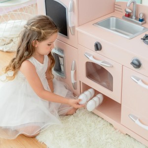 Mädchen spielt mit rosa Teamson Kids Spielküche mit Herd, Ofen und Zubehör.