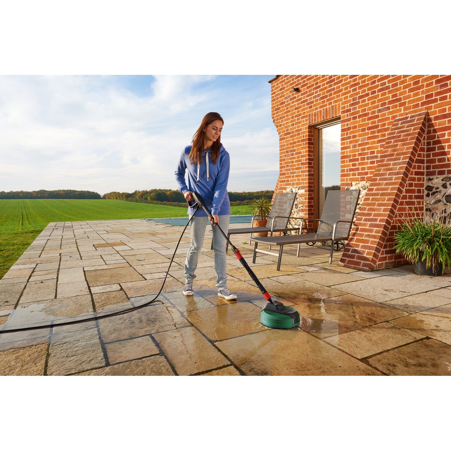 Frau reinigt Terrasse mit Bosch Aquasurf 280 Flächenreiniger. Schwenkbarer Kopf für einfache Handhabung.