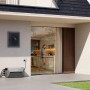 Anker Solix Balkonkraftwerk-Set mit Solarbank 2 E1600 Pro vor Hauswand mit Frau in Küche.