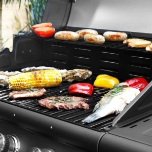 Schwarzer Taino Gasgrill mit Steaks, Fisch, Gemüse, Würstchen und Maiskolben auf dem Rost. Perfekt für BBQ.