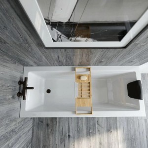 Weiße Rechteckbadewanne mit Bambus Badewannenablage, schwarzer Kopfstütze und dunkler Armatur. OBI Badewannen.