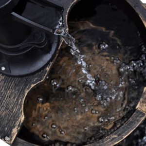 Detailaufnahme: Kaskadenbrunnen im Vintage-Design mit Handwasserpumpe und fließendem Wasser.