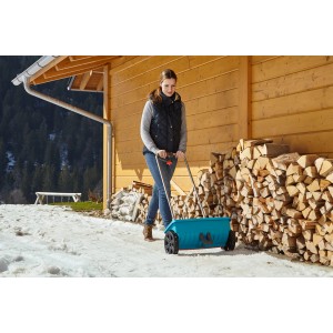 Frau benutzt Gardena Streuwagen L zum Ausbringen von Streugut im Winter.