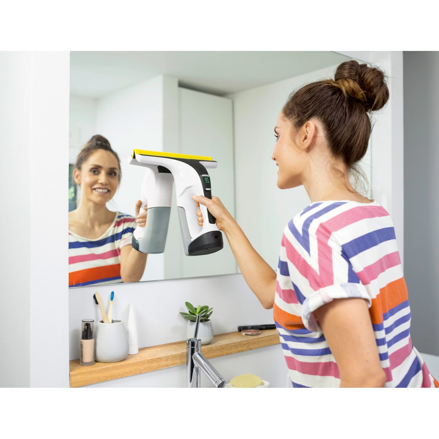 Frau reinigt Spiegel mit Kärcher Akku-Fenstersauger WV 6 Plus für streifenfreie Sauberkeit.