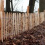 Staketenzaun aus Haselnuss mit Holzpfosten (1,5m, Ø 6-9cm) im Garten.