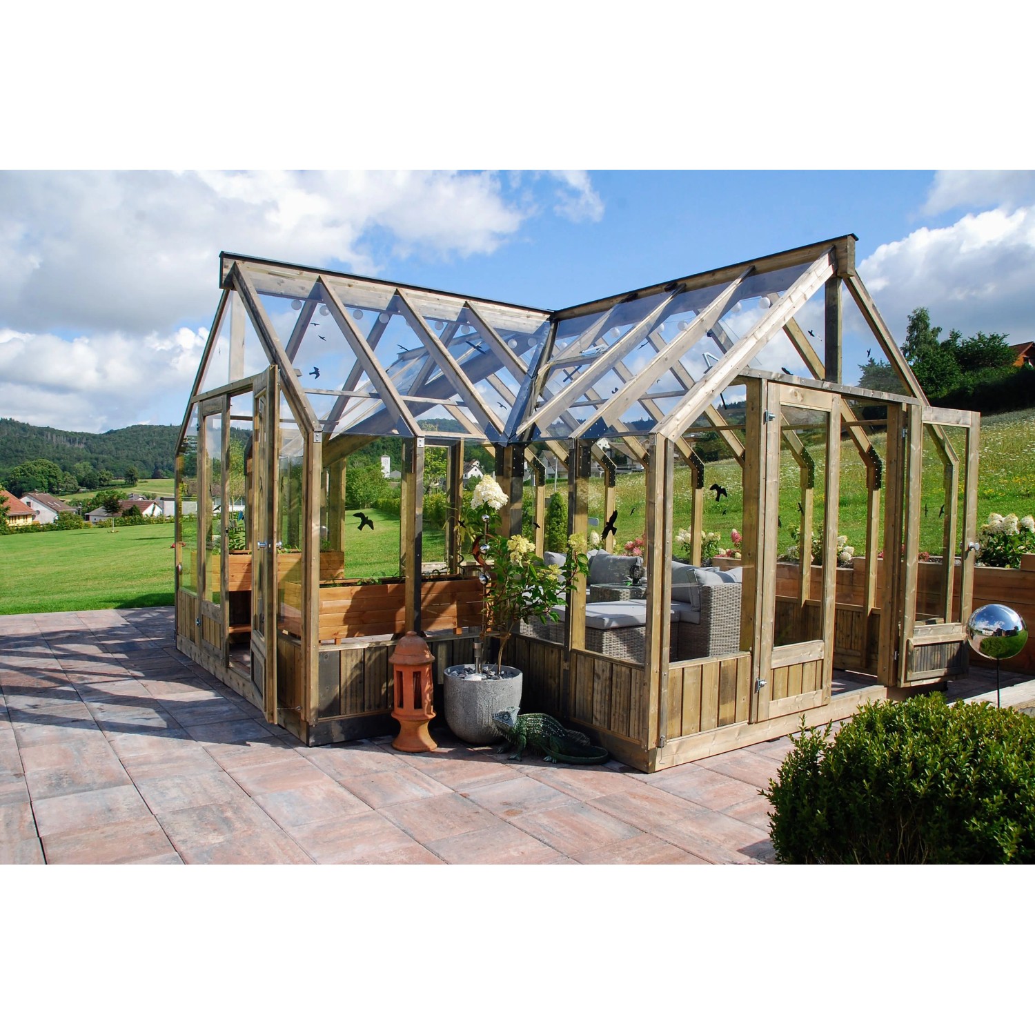 Palmako Gewächshaus Emilia 19 aus Holz und Glas, grau, mit Pflanzen und Sitzbereich.