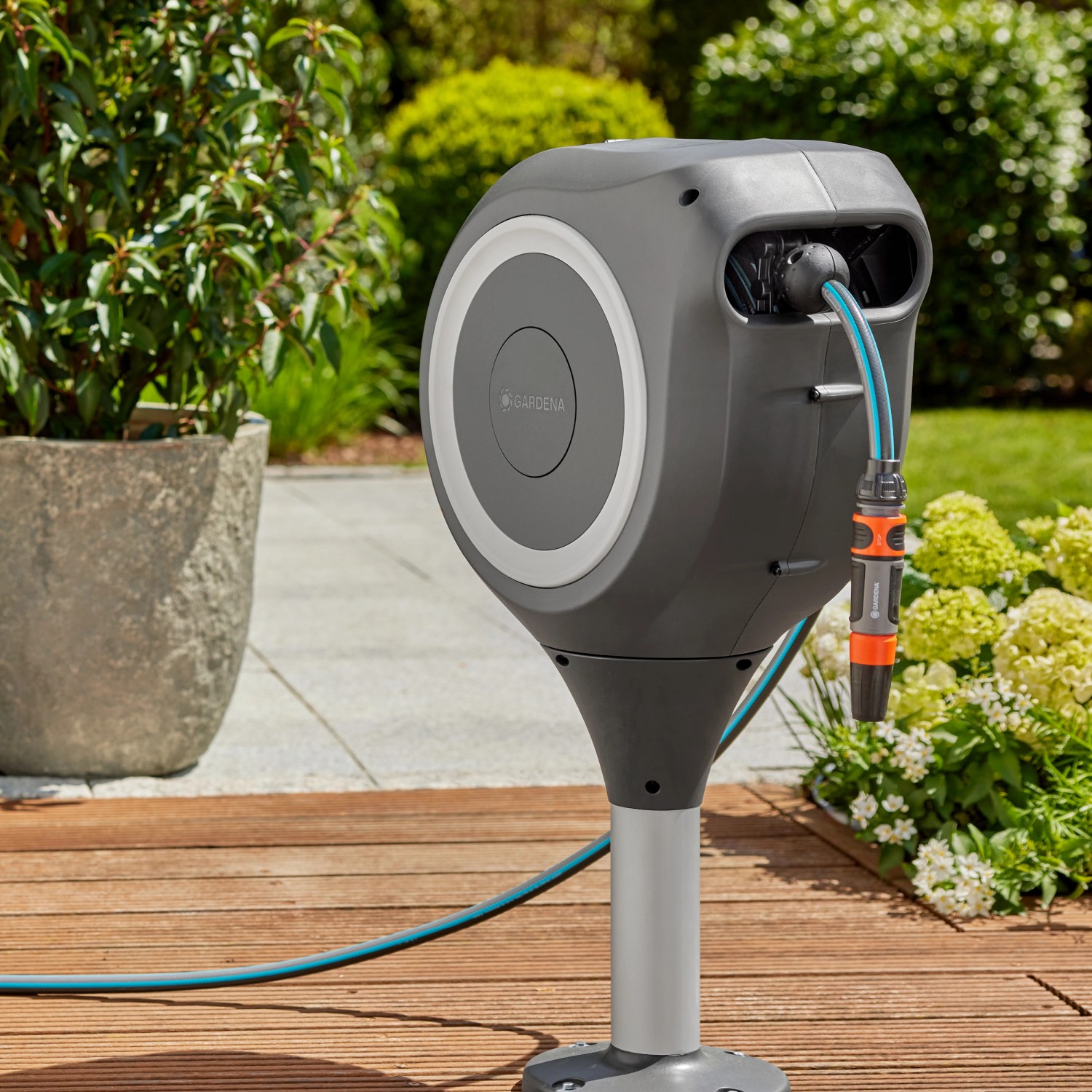 Gardena Terrassen-Schlauchbox RollUp M mit 20m Schlauch auf Holzterrasse im Garten.