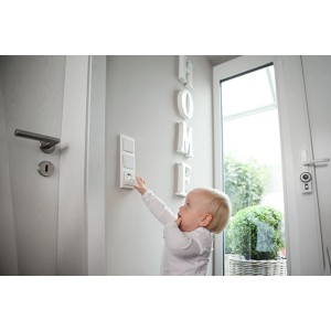 Kind mit Abus Steckdosenschutz JC2100A Greta an Steckdose. Kindersicherung für mehr Sicherheit.