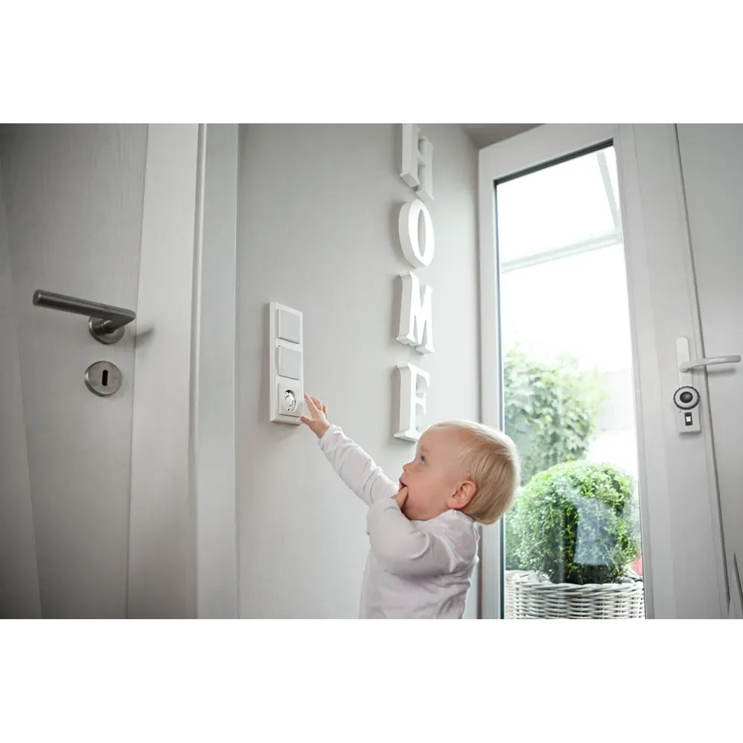 Kind mit Abus Steckdosenschutz JC2100A Greta an Steckdose. Kindersicherung für mehr Sicherheit.
