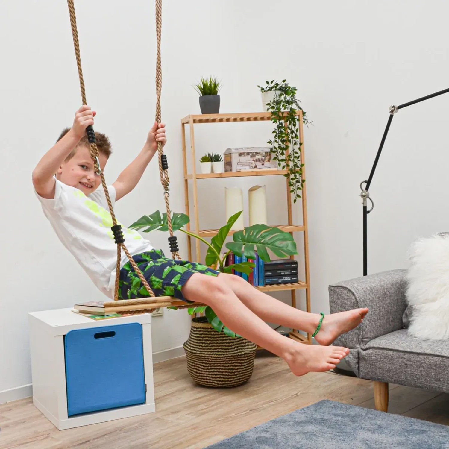 Kind schaukelt auf LittleTom Brettschaukel (braun) im Wohnzimmer. Holzschaukel für drinnen.