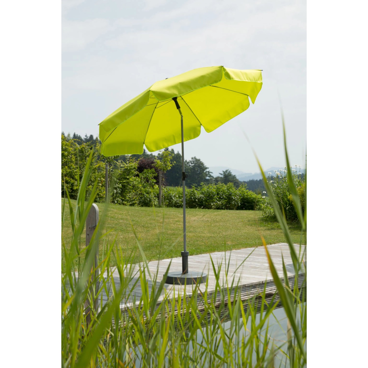 Apfelgrüner Schneider Balkonschirm Locarno Ø 200 cm mit Knickfunktion im Garten.