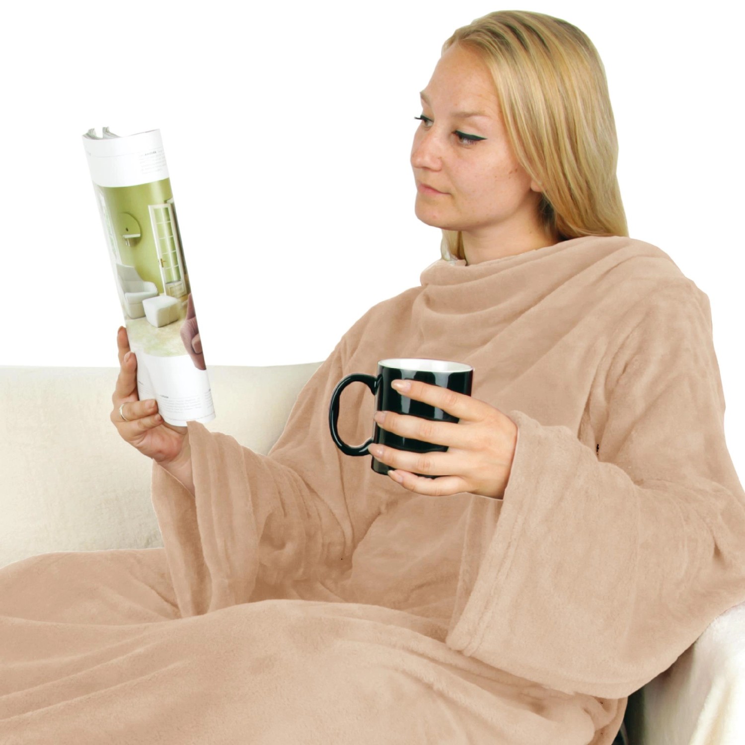 Frau mit beiger Bestlivings Kuscheldecke mit Ärmeln und Tasse auf dem Sofa.