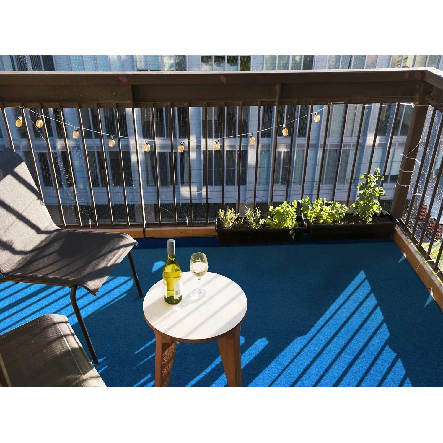 Blauer Primaflor Rasenteppich Park auf Balkon mit Möbeln und Getränken.