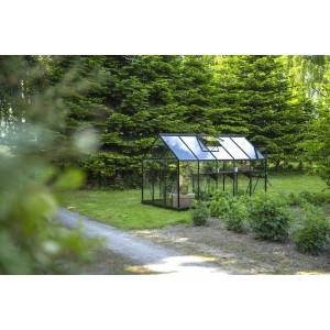 Schwarzes Halls Gewächshaus Popular 106 mit 6,2 m² im Garten, umgeben von Grün.