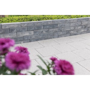 Diephaus Mauerstein Patea Pico, weiß-schwarz, als Gartenmauer mit Bepflanzung und Pflastersteinen.