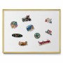 Weiße Magnettafel mit goldenem Rahmen, an der Wand hängend, mit bunten Reisemagneten für Notizen und Fotos.