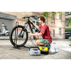Mann reinigt Fahrrad mit Kärcher OC 3 und Ansaugschlauch. Schlauch verbindet Reiniger mit Wasserbehälter.