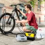 Mann reinigt Fahrrad mit Kärcher OC 3 und Ansaugschlauch. Schlauch verbindet Reiniger mit Wasserbehälter.