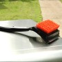 Char-Broil Grillbürste Cool Clean Premium mit Borsten und Schaber auf einem Grill.