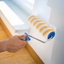 LUX Dispersionswalze 25cm in Aktion: Streichen einer Wand mit gelb-weiß gestreifter Farbwalze.