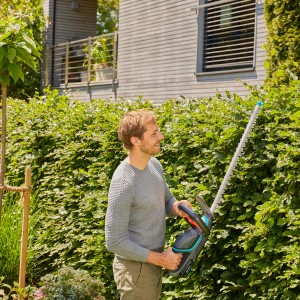 Mann schneidet Hecke mit Gardena Akku-Heckenschere ComfortCut 60/18V P4A. Inkl. Akku-Set.