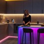 Moderne Küche mit Frau, die Gemüse schneidet. Smarte Beleuchtung. Philips Smart Steckdose für Automation & Energieüberwachung.