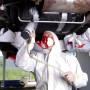 Anwendung: Person lackiert mit Schutzanzug und Maske ein Auto mit einem Kompressor.