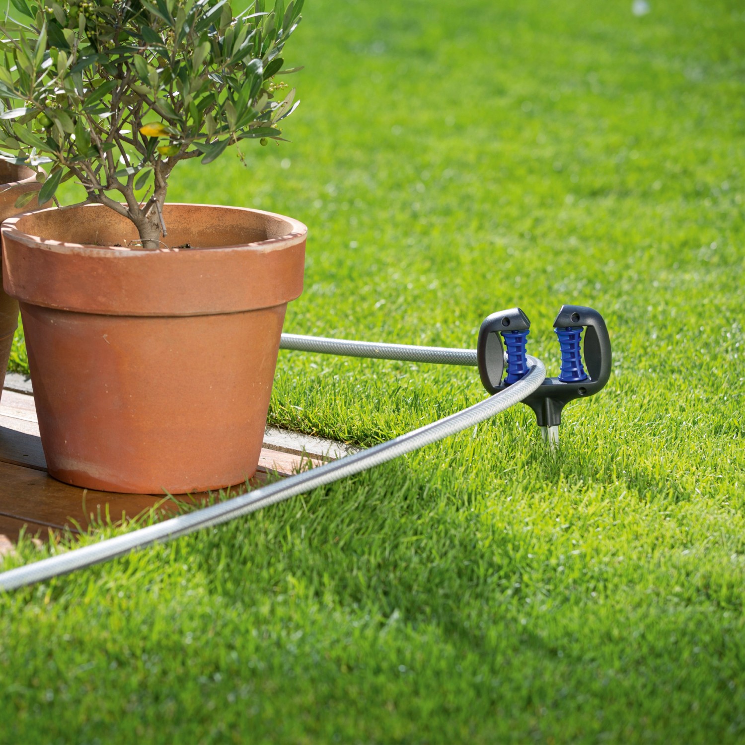 LUX Schlauchführung mit Erdspieß im Garten, leitet Schlauch um Topfpflanze.