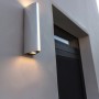 Verchromte Lutec LED-Außenwandleuchte LEO mit Up- & Downlight und Lichtstreifen an einer weißen Hauswand.