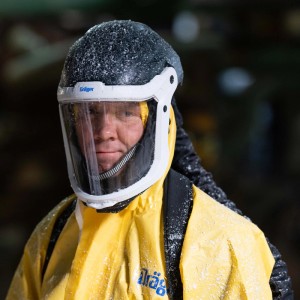 Gelber Dräger Schutzanzug SPC 4400 mit Helm und Visier, bedeckt mit Partikeln. Schutzkleidung für Labor & Lackierarbeiten.