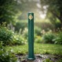Grüne Wasserzapfsäule aus Aluminium im Antik-Design mit goldenem Wasserhahn, freistehend im Garten bei Regen.