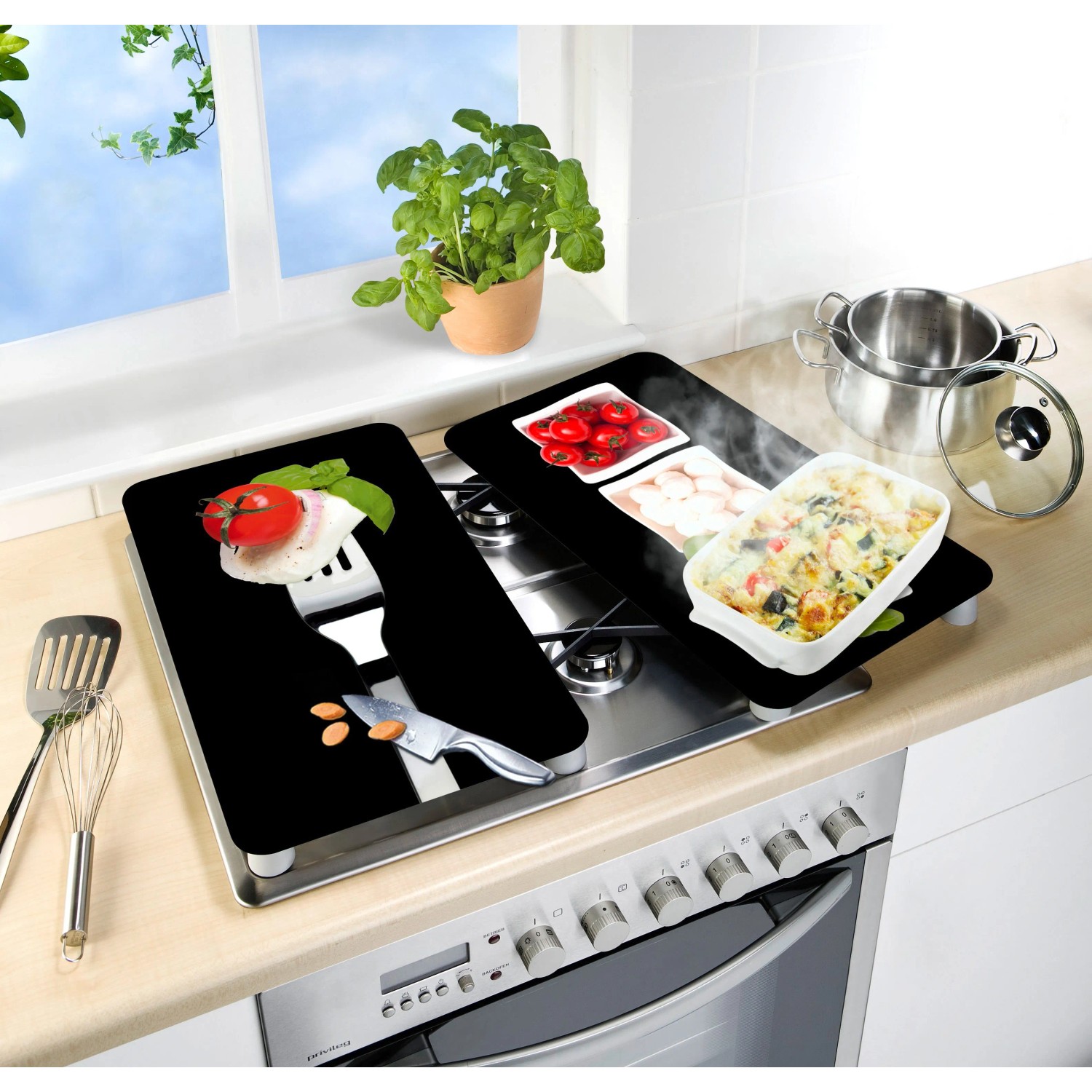Wenko Herdabdeckplatten Caprese 2er Set auf einem Herd mit italienischen Zutaten Motiven.
