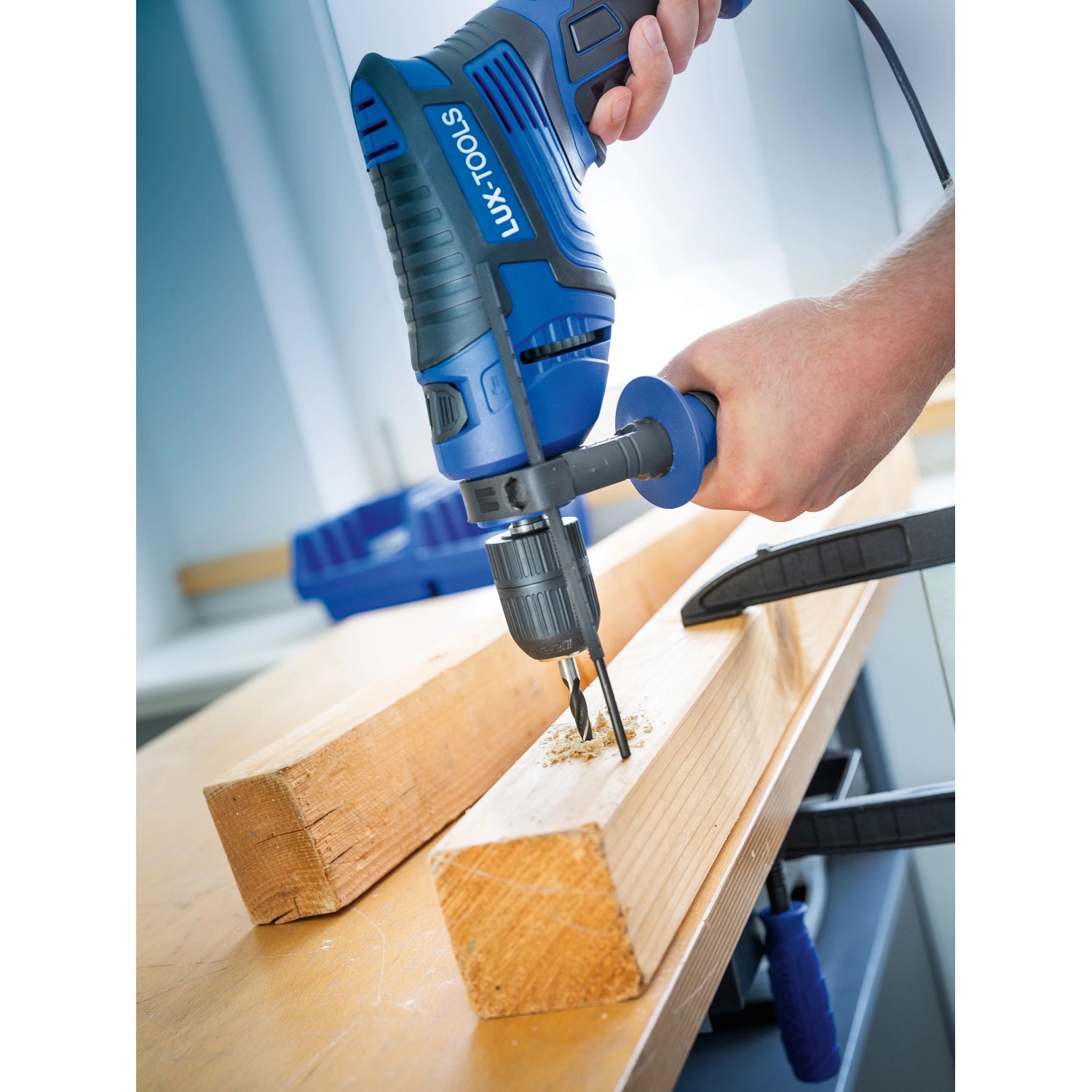 Blaue LUX Schlagbohrmaschine E-BMS-21 mit Tiefenanschlag bohrt in Holz.