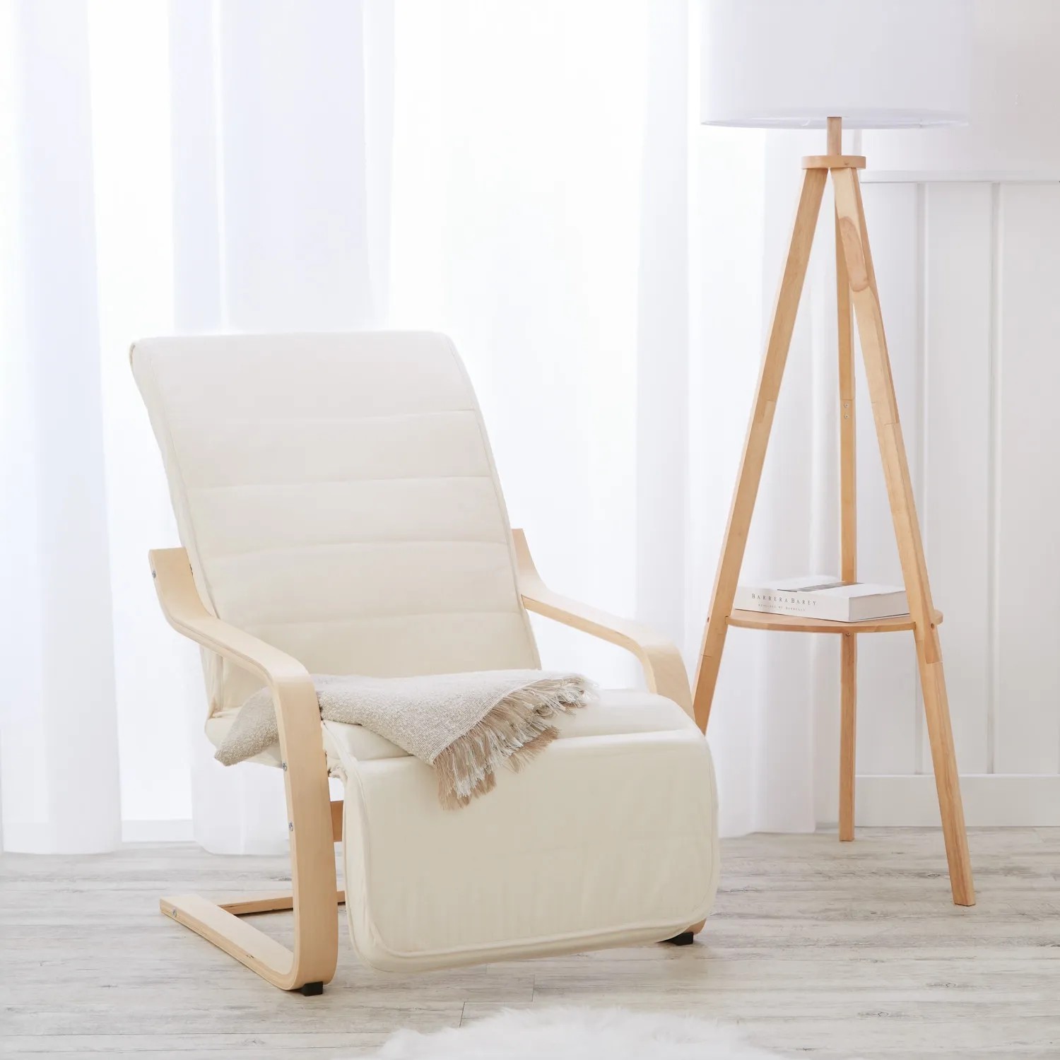Beiger Relaxsessel mit Fußstütze und hellem Holzgestell neben einer Stehlampe.