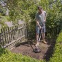 Mann benutzt Al-Ko Akku-Motorhacke TLD 1820 im Garten zur Bodenbearbeitung.