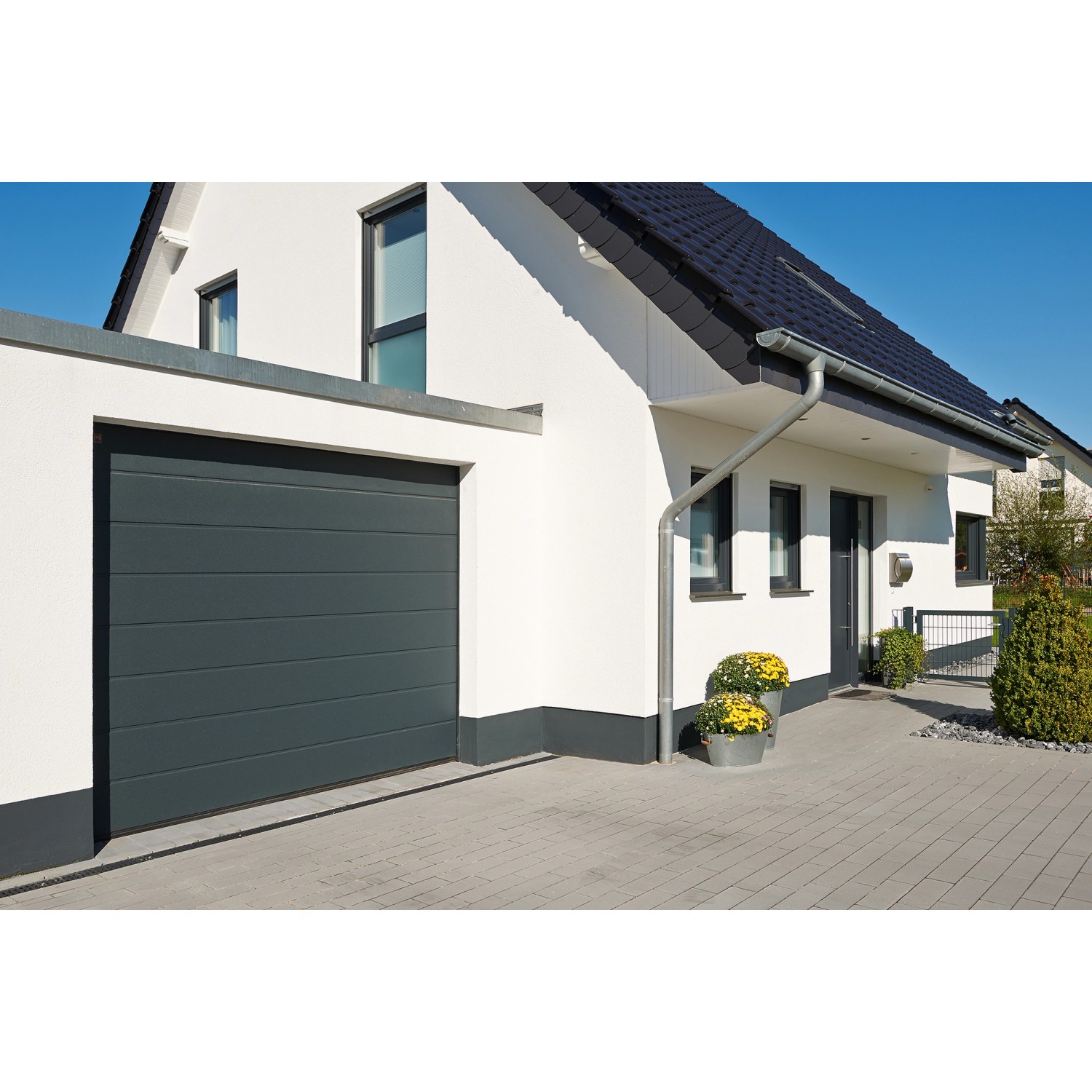 IsoMatic Garagentor, anthrazitgrau, mit Antrieb, am Haus montiert.