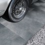 Graue Cersanit Terrassenplatten in Betonoptik, verlegt im Außenbereich neben einem Oldtimer und Kies.