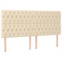 Cremefarbenes Boxspringbett Kopfteil mit Knopfheftung, Stoffbezug und Holzfüßen.