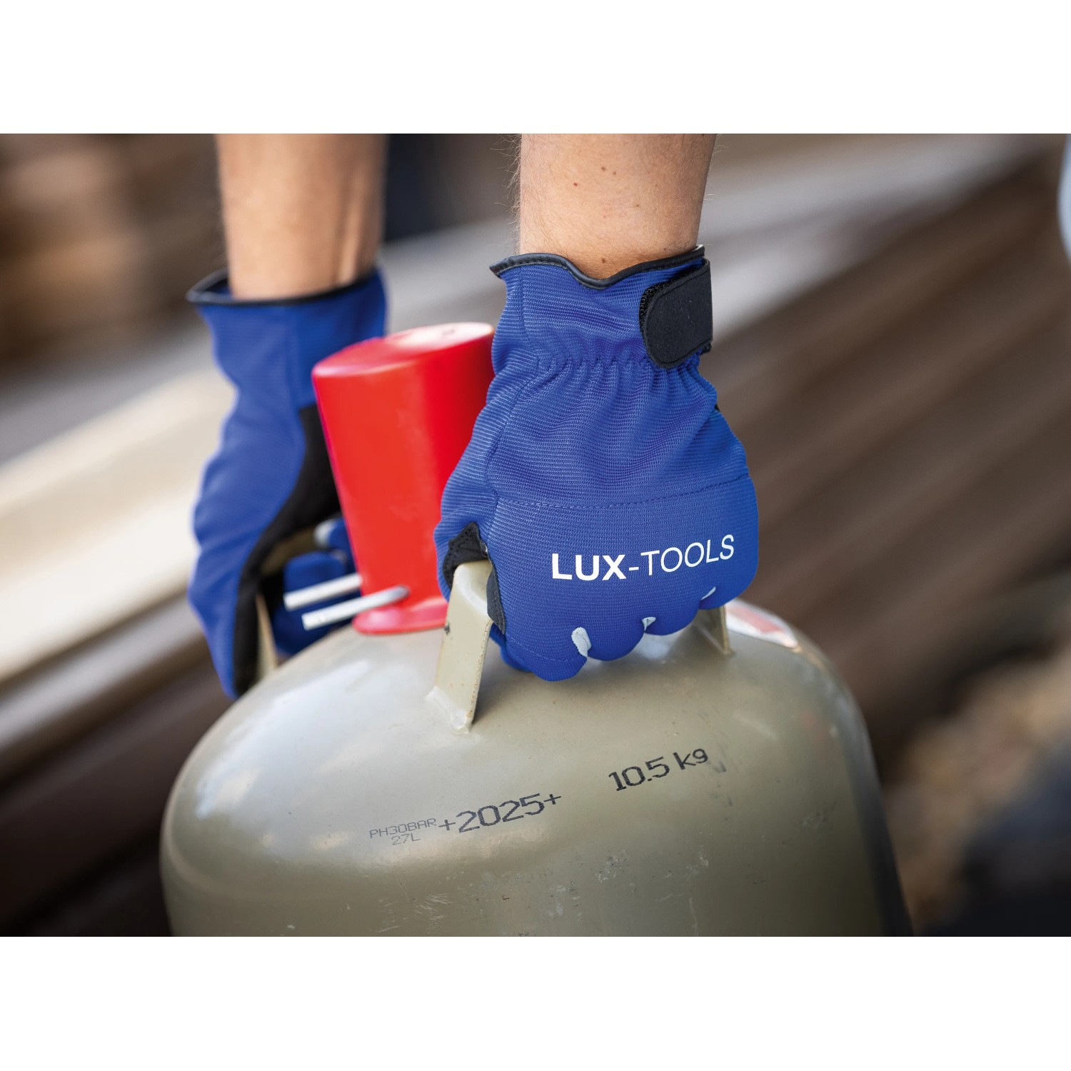 Hände mit blauen LUX Arbeitshandschuhen Tough Gr. 8 tragen eine Gasflasche.