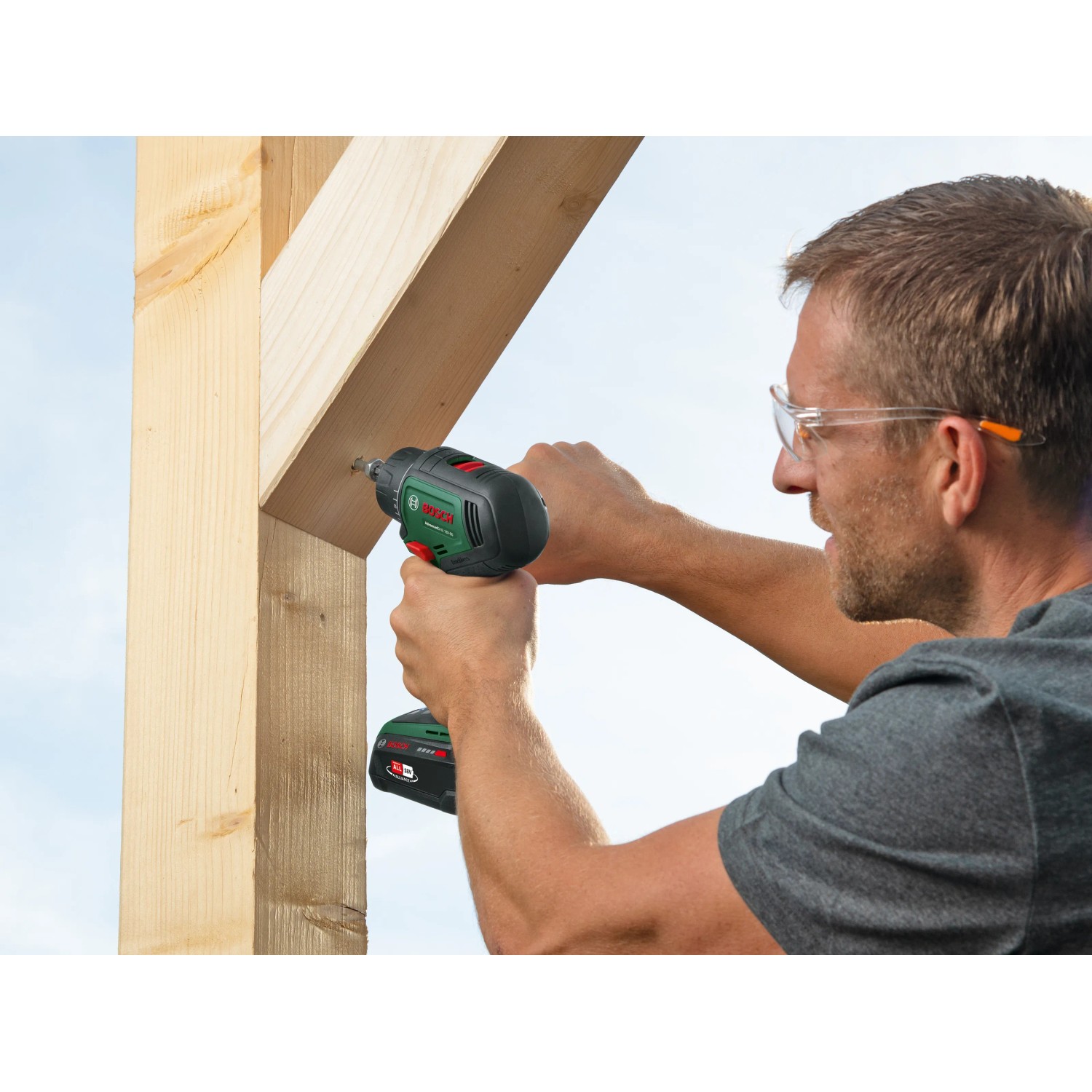 Mann schraubt mit Bosch 18V Akku-Bohrschrauber Advanced Drill 18 V-80 Solo eine Schraube in ein Holzbrett.