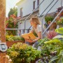 Gardena Bewässerungscomputer Flex am Wasserhahn mit Frau auf Treppe im Garten.
