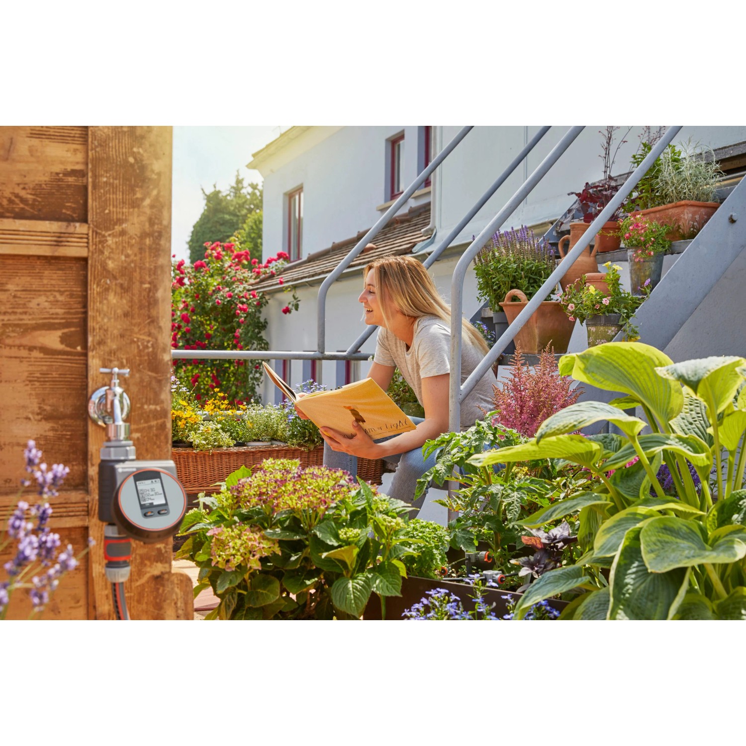 Gardena Bewässerungscomputer Flex am Wasserhahn mit Frau auf Treppe im Garten.