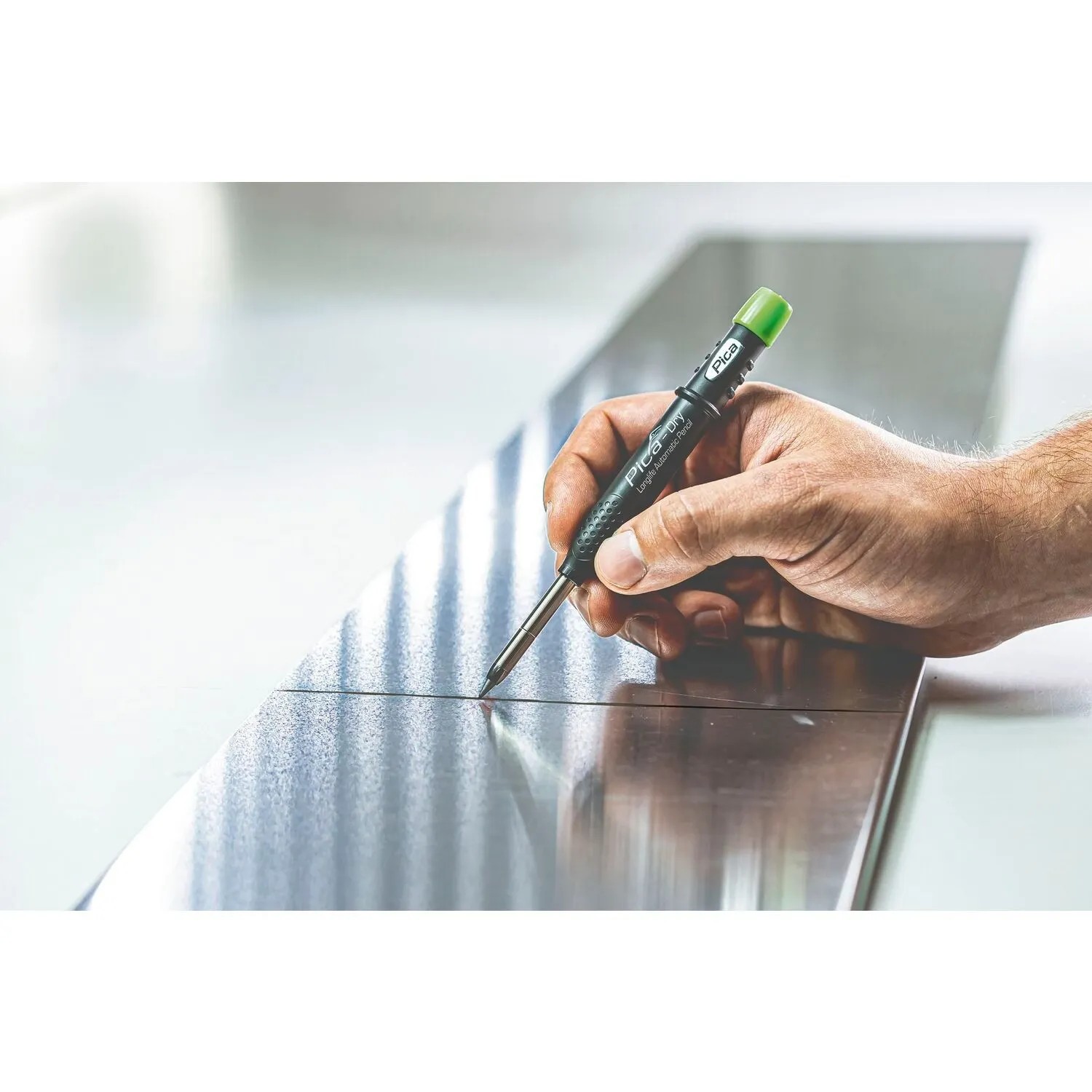 Hand markiert mit Pica Dry Tieflochmarker präzise eine Linie auf Metall. Graphit 2B Druckbleistift für Handwerkzeuge.