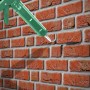 Grüne Kartuschenpistole füllt Risse in einer Ziegelwand mit MEM Reparatur-Mörtel (zementgrau).